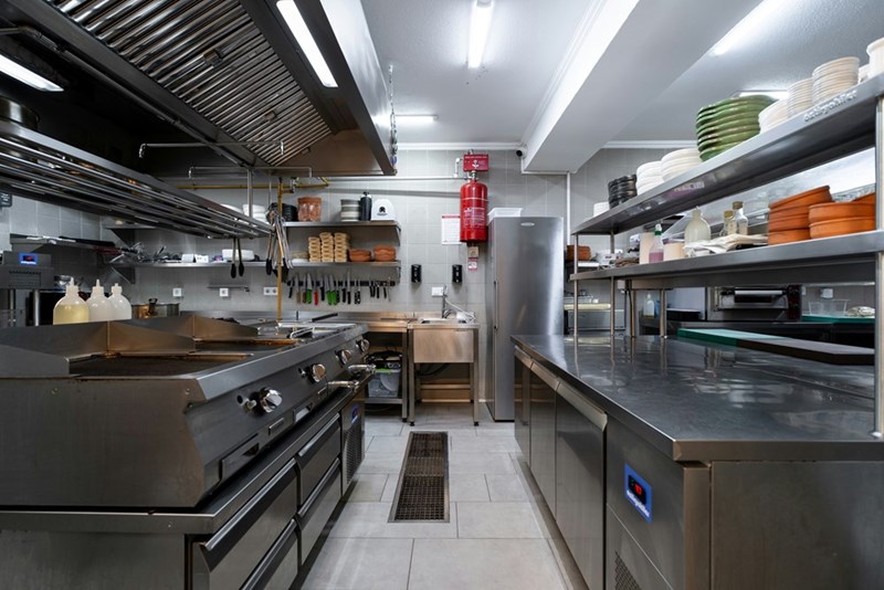 Industrial kitchen, clean and neat after closing time, as represented in a photo.