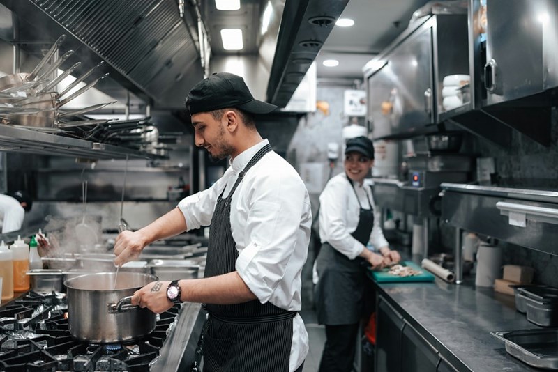 Kitchen workers realizing they won't be able to eat free meals this week after a workplace incident, as a pair of models display.