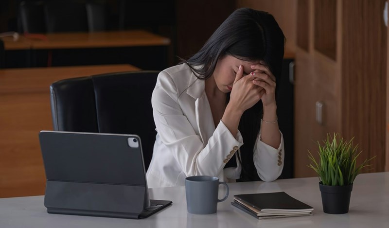 Stressed businesswoman in front of a laptop, presented by a model.