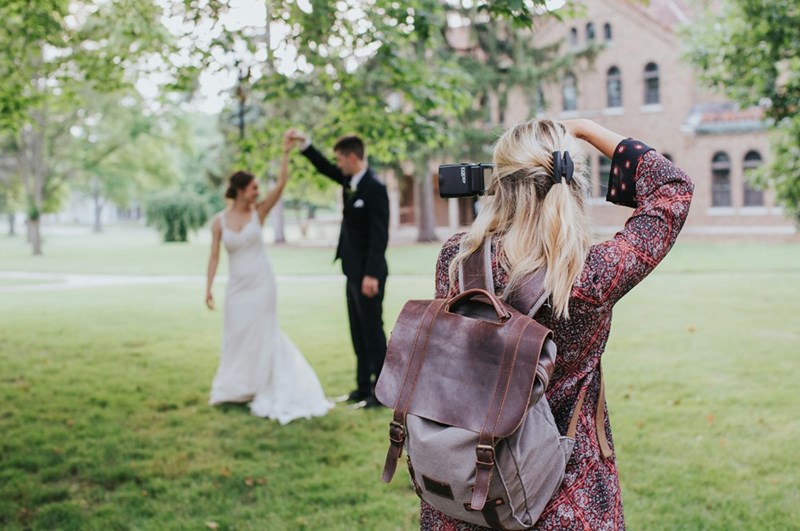 Wedding photographer snaps a picture of a bride and groom, in a depiction by models.