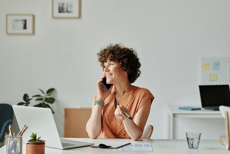 Woman grins while telling boss that she's quitting her job, as shown in a representation by a model.