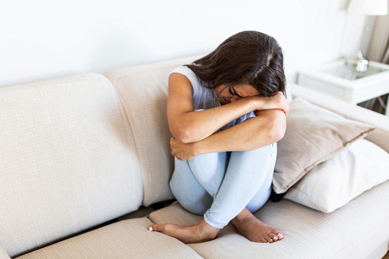 A representation of a hopeless, young woman curled up on her couch.