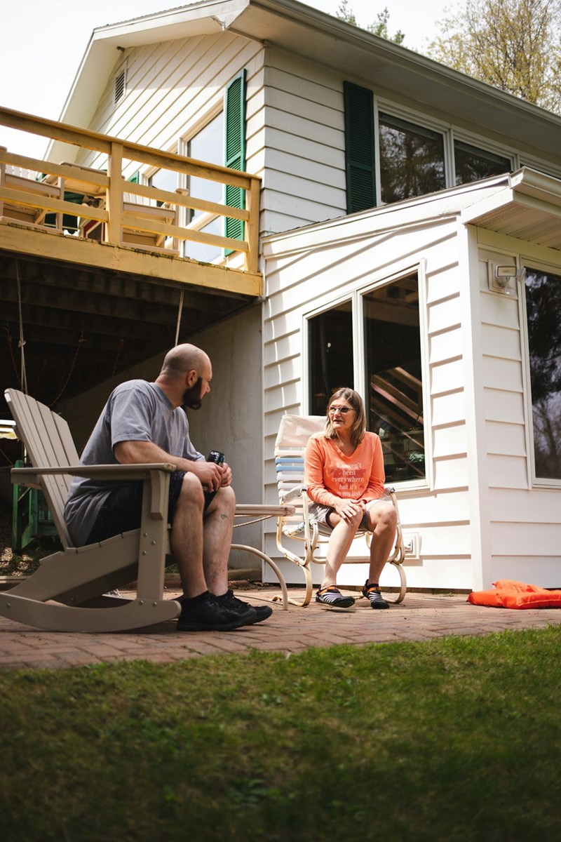 A portrait depicting a male and female homeowner having a conversation outside their house.