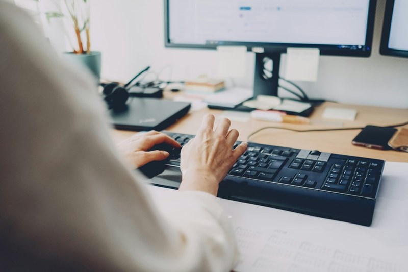 An employee types on their keyboard with their desktop computer (model)