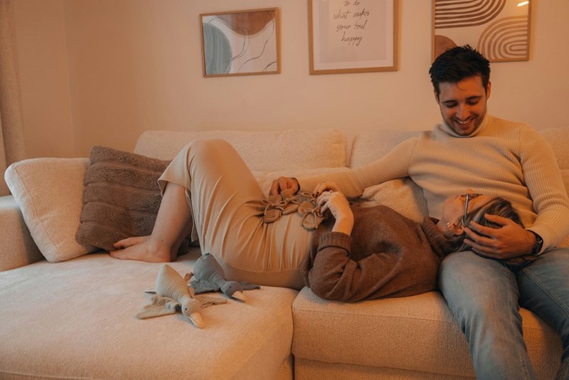 Man sitting on a couch with his girlfriend laying her head on his lap.