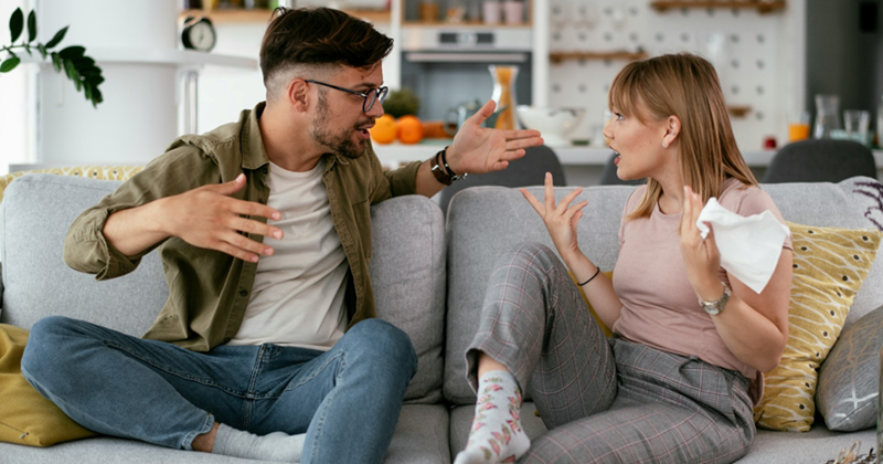 A representation of a man and a woman sitting on a couch, arguing with one another