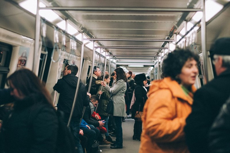 Passengers stand and sit inside a crowded subway car as they make their way through the city during a busy commute.