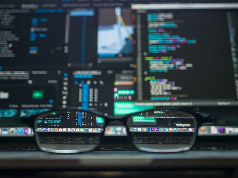 closeup photo of eyeglasses in front of computer screens