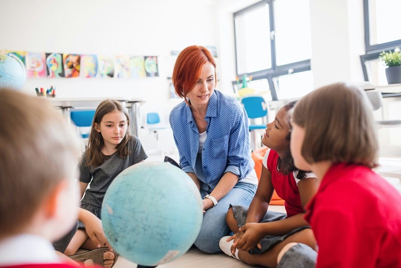 Middle school teacher and her students work together on a lesson, as depicted by models.