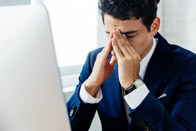 Businessman (model) looking stressed at the computer.