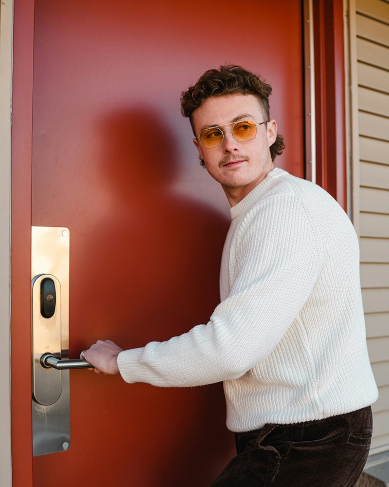 A male model opening a red door