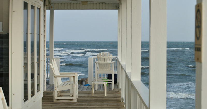 A representation of the wraparound porch of a house right next to the ocean