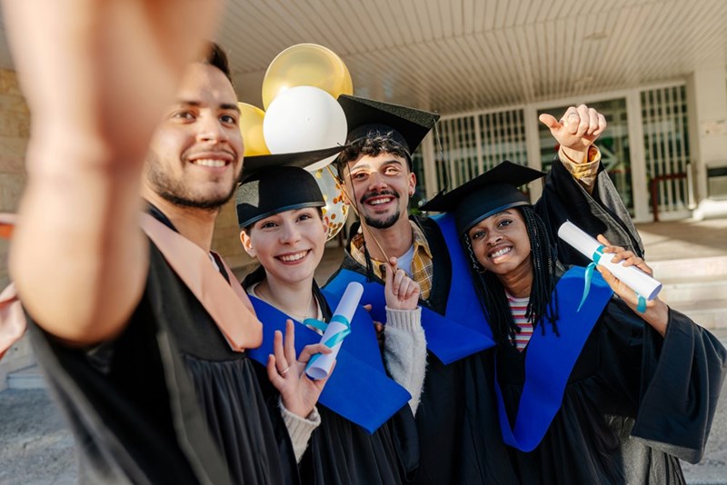 Friend group of graduates snap a selfie together, in a depiction by models.