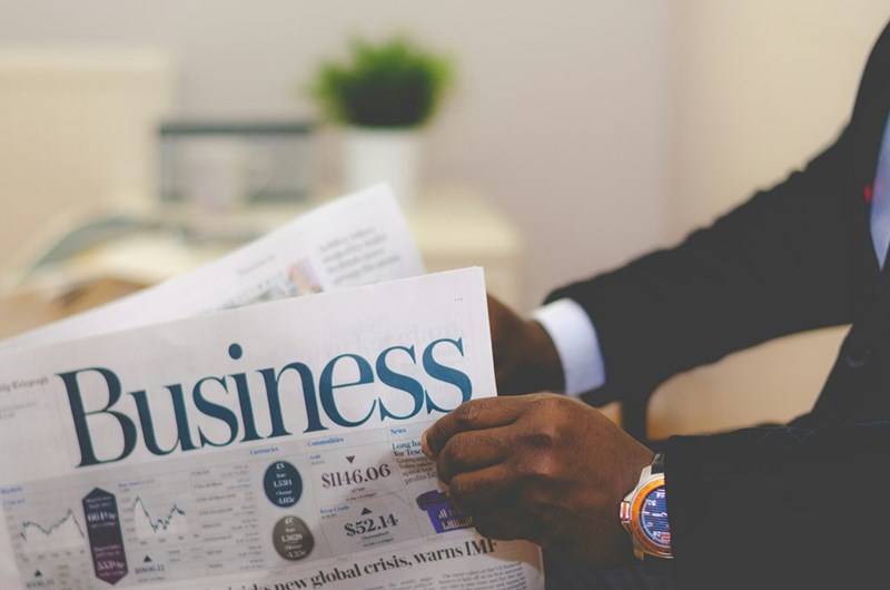 person wearing a suit reading business newspaper