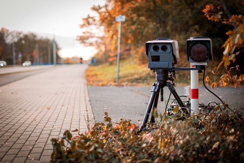 A speeding camera sitting on the street.