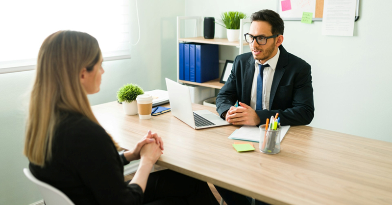 A representation of a male manager and a female employee having a discussion while sitting on opposite sides of a desk
