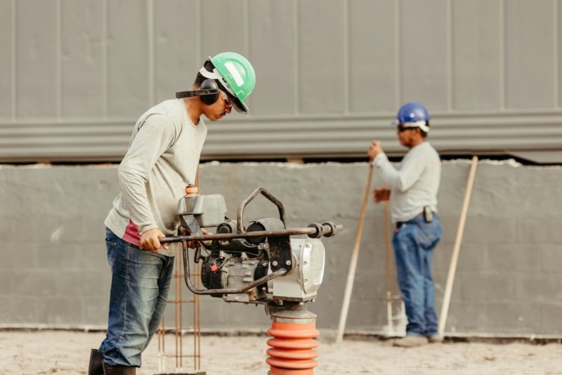 Construction workers operate machinery, causing a thick coating of dust in their area, as represented by models.