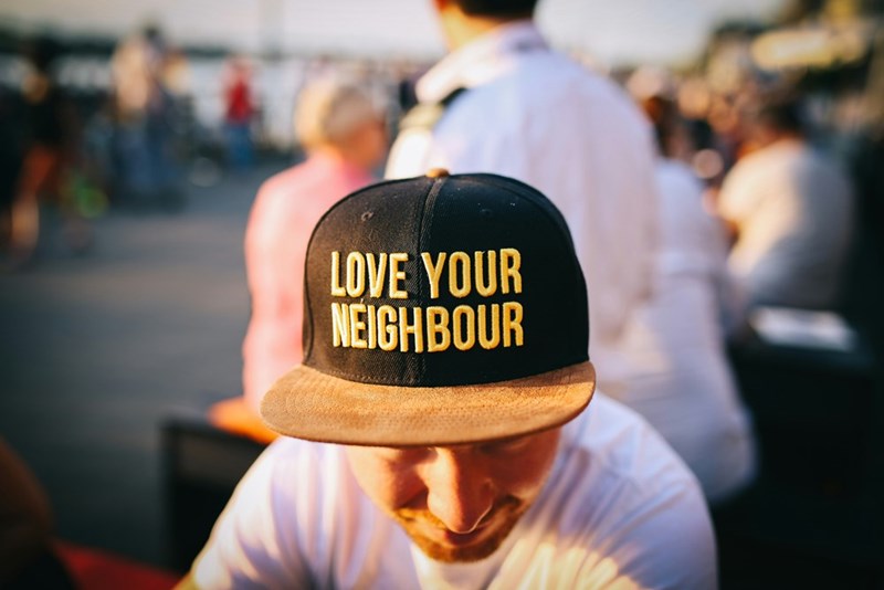 man wearing a cap that says 'love your neighbour'