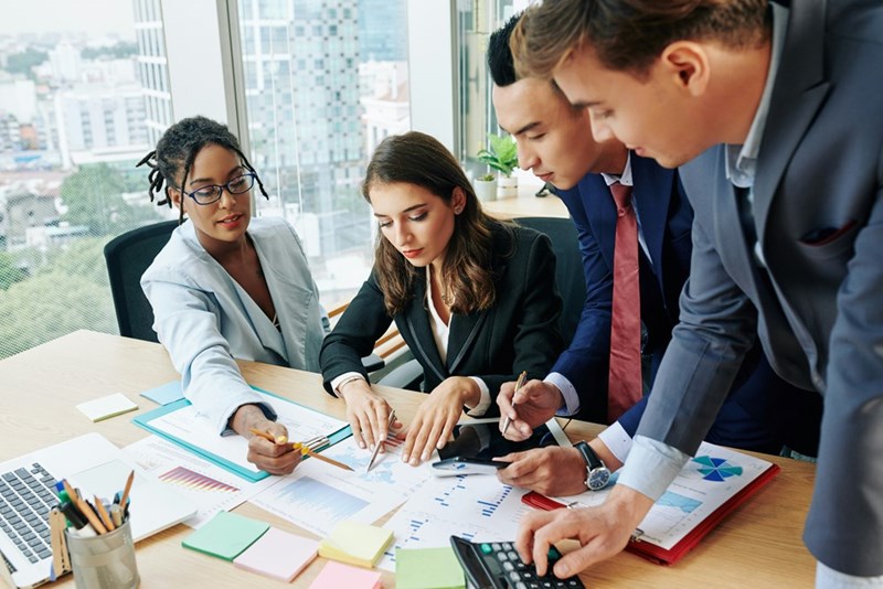 A depiction of a group of employees looking at documents from a company survey. Not actual subjects.