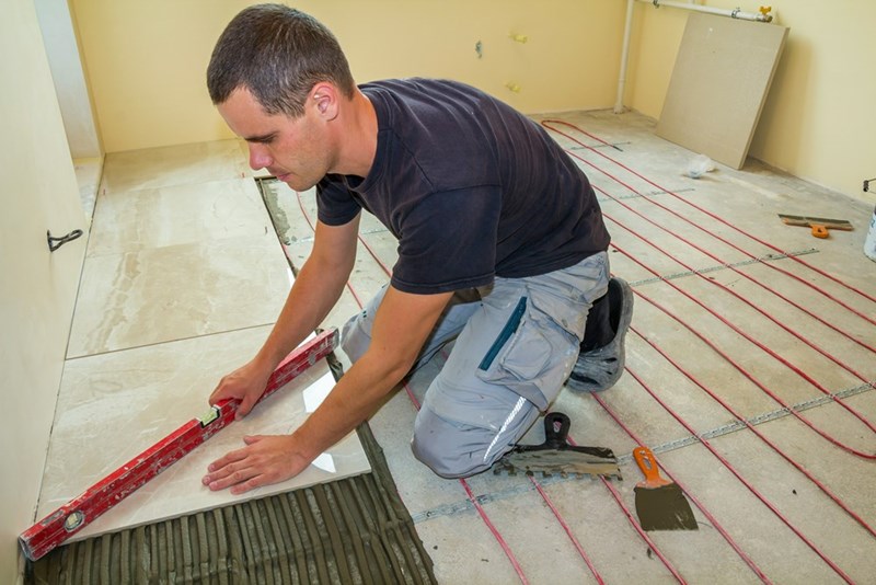 Young worker installing tiles ceramic of a bathroom floor.