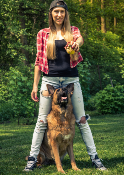 A woman and a German Shepherd dog playing with a ball in the park, represented by models.