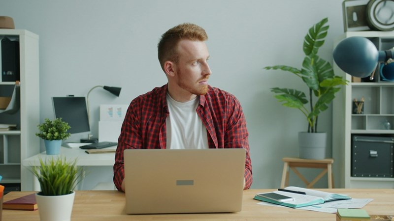 Remote worker taking a thoughtful pause between tasks in a bright and organized workspace.