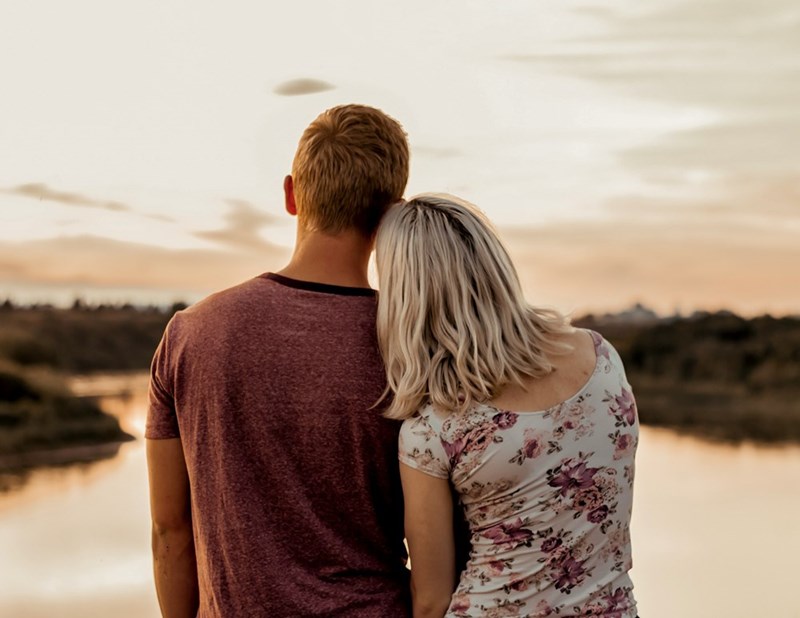 Couple watching the sunset by the water, reflecting on love, companionship, and a shared future.