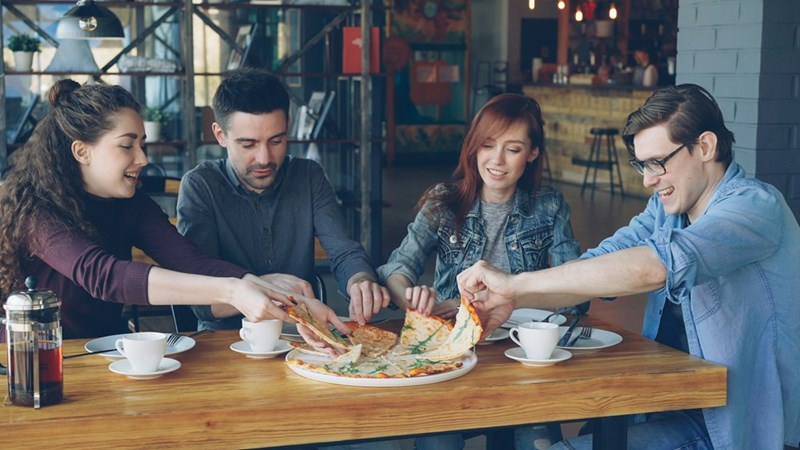 friends sharing pizza at a restaurant