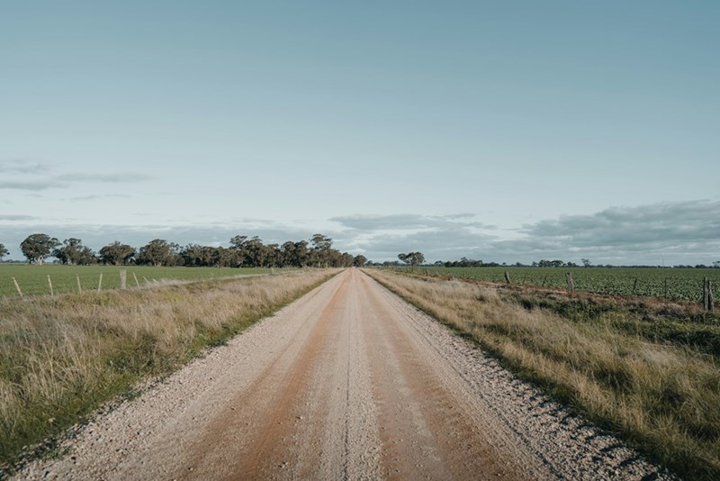 A dirt road going through fields under a beautiful blue sky in a farming community (stock).