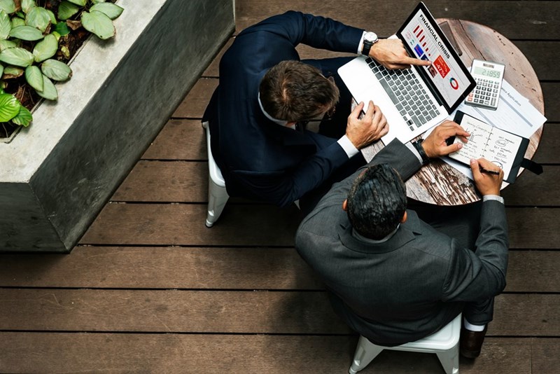 Business men sitting down at a table wearing a suit and looking at some papers.