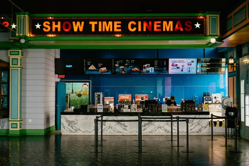 A movie theater cinema with a bright showtime sign and concession stand (stock).