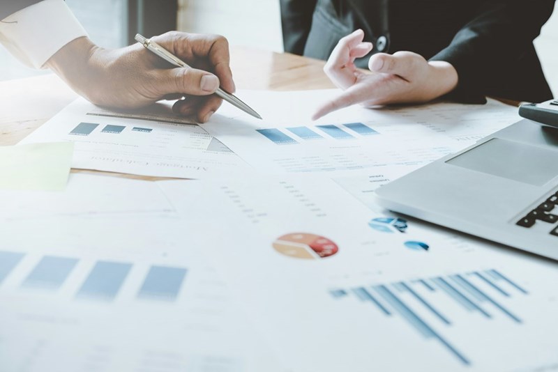 Management look at over-performing employees' figures, representative of the events of the story.