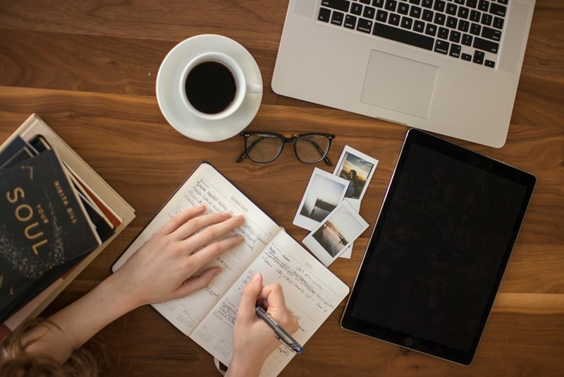 person holding a pen writing on notebook