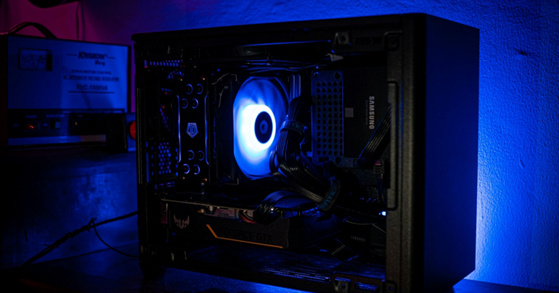 A representation of a gaming PC emitting a blue light in a dark room