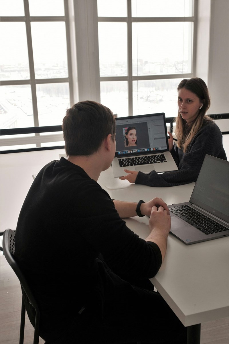 A man and a woman (models) holding laptops, talking about a candidate
