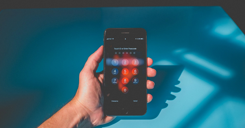 A representation of a hand holding an iPhone with its lock screen open against a blue background