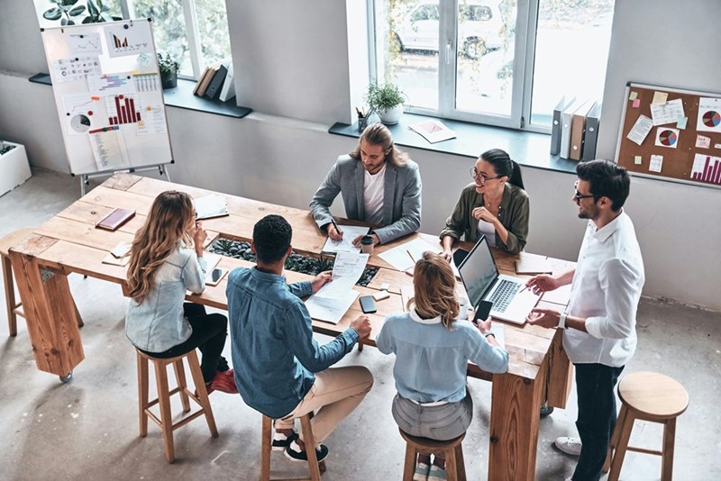 A representation of a group of employees gathered around a conference table during a team meeting.