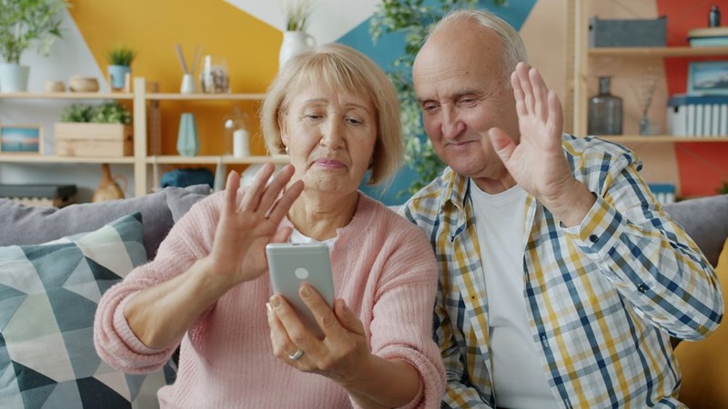 A representation of an older couple making a video call on a smartphone from their living room.