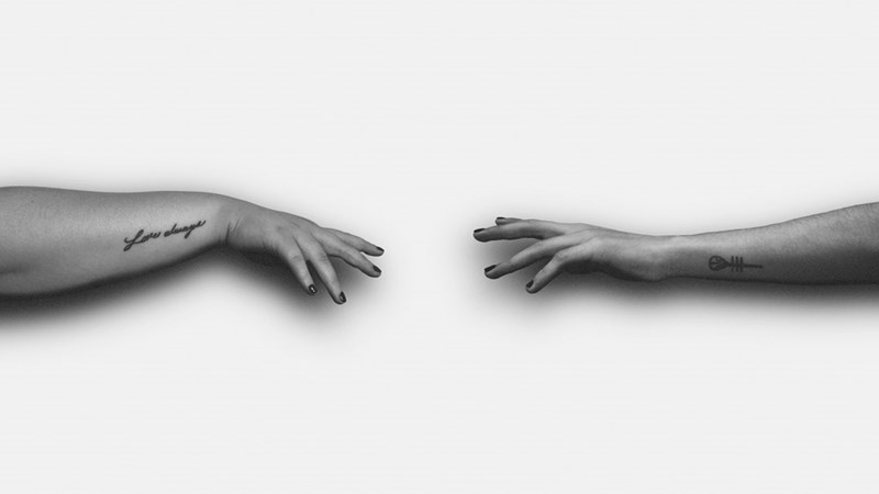 grayscale photo of two hands trying to reach each other