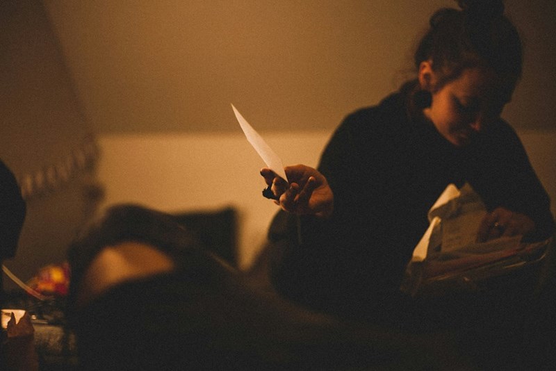 A woman sitting in a room with poor light holding papers.