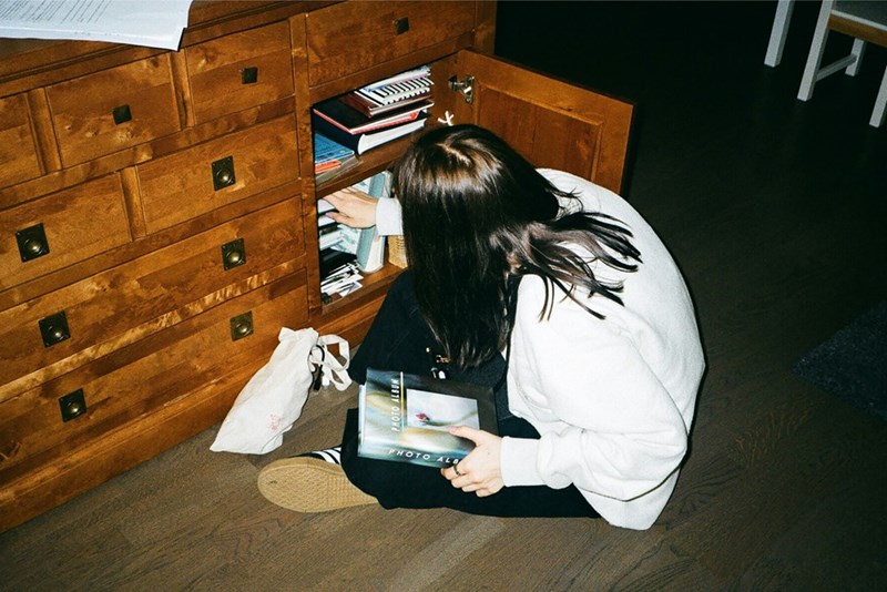 Woman sitting on the floor at night searching through a cabinet with papers.