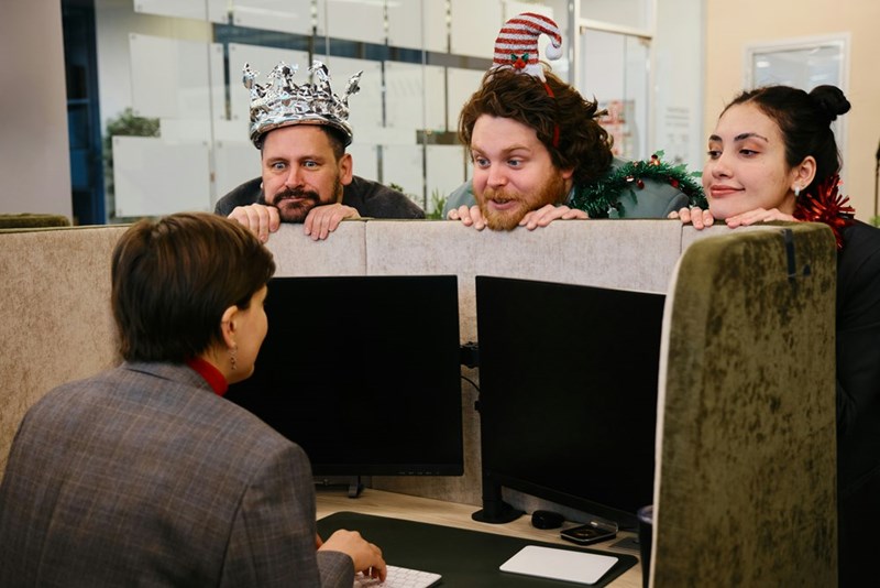 Employees in holiday costumes talking to a working coworker, displayed by models.