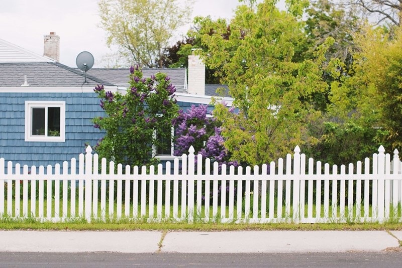 A representation of a white picket fence surrounding a residential property in a quiet neighborhood.