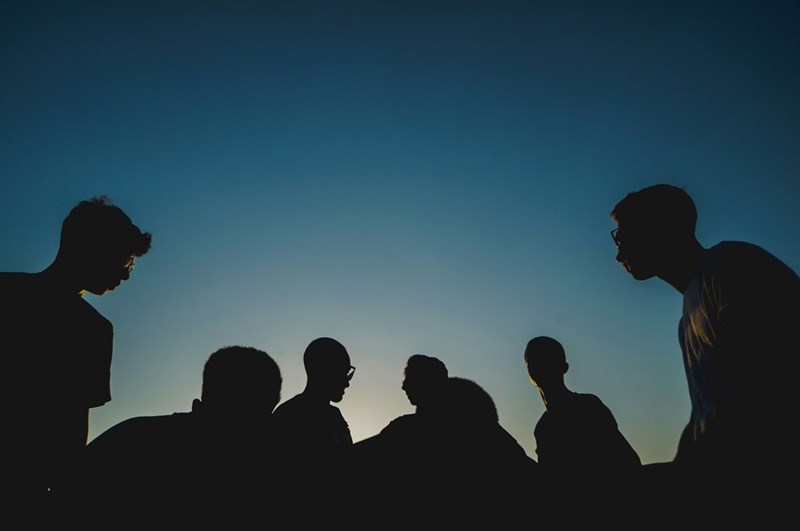 silhouette photo of a group of men under the night sky