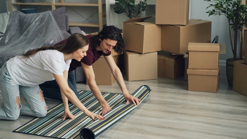 a man and woman laying on a rug with cardboard boxes all around