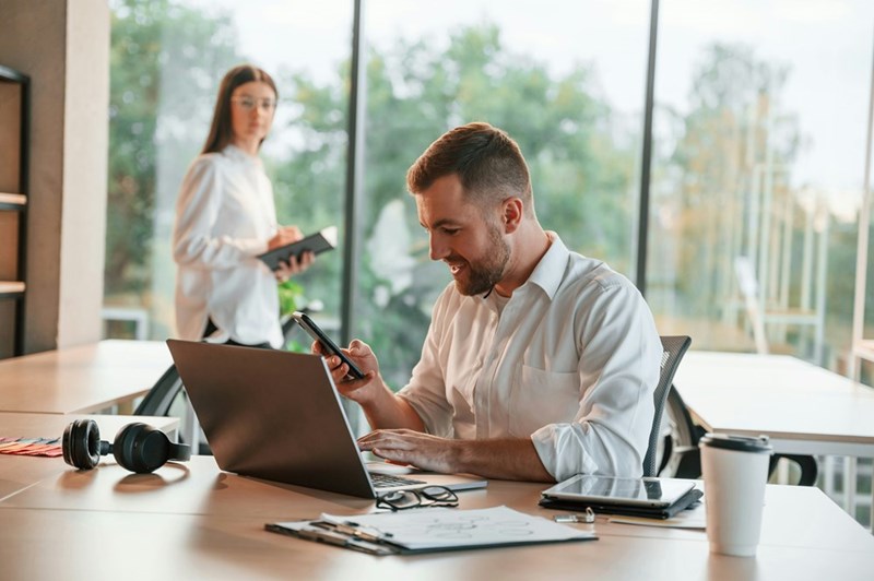 A manager checks his phone while working from home