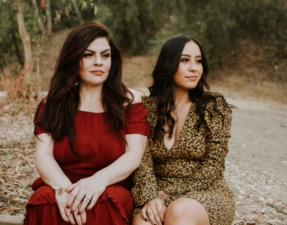 Two models representing the stepmother in a red dress and stepdaughter in polkadots
