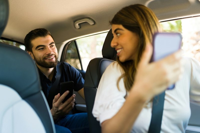 Happy female driver and passenger looking at the GPS on the mobile app on the smartphone while driving to a destination, depicted by models.