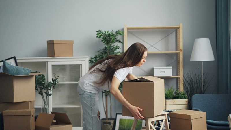 Young woman packing boxes while moving into a new home.