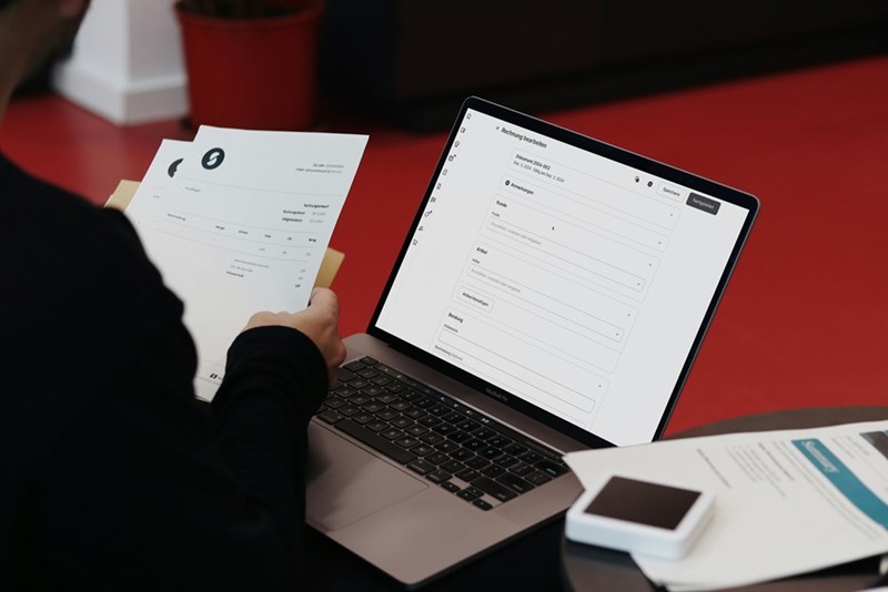 a person sitting at a desk with a laptop and papers